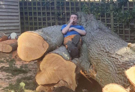 man laying on cut down tree